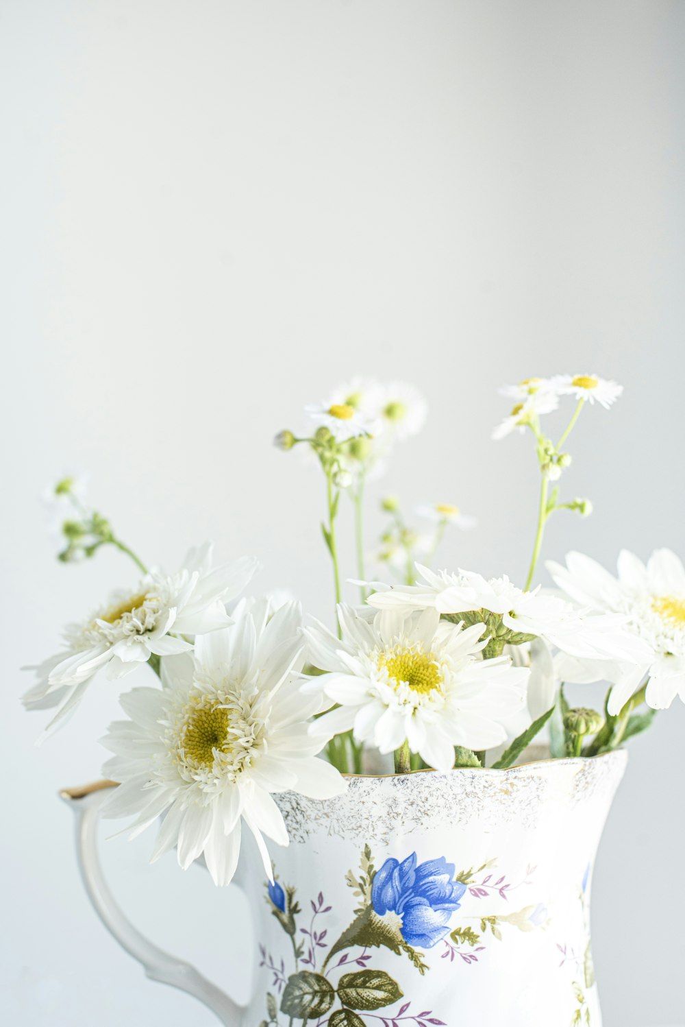 white and yellow flowers in white ceramic vase