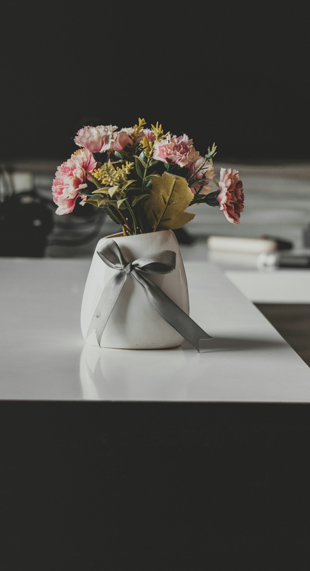 pink and yellow flowers in white vase on table