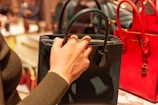 person holding black leather handbag