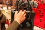 person holding black leather handbag