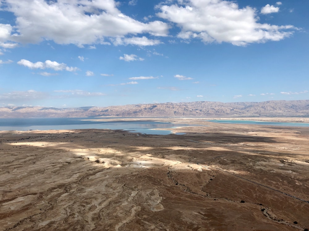 brown sand near body of water under blue sky during daytime