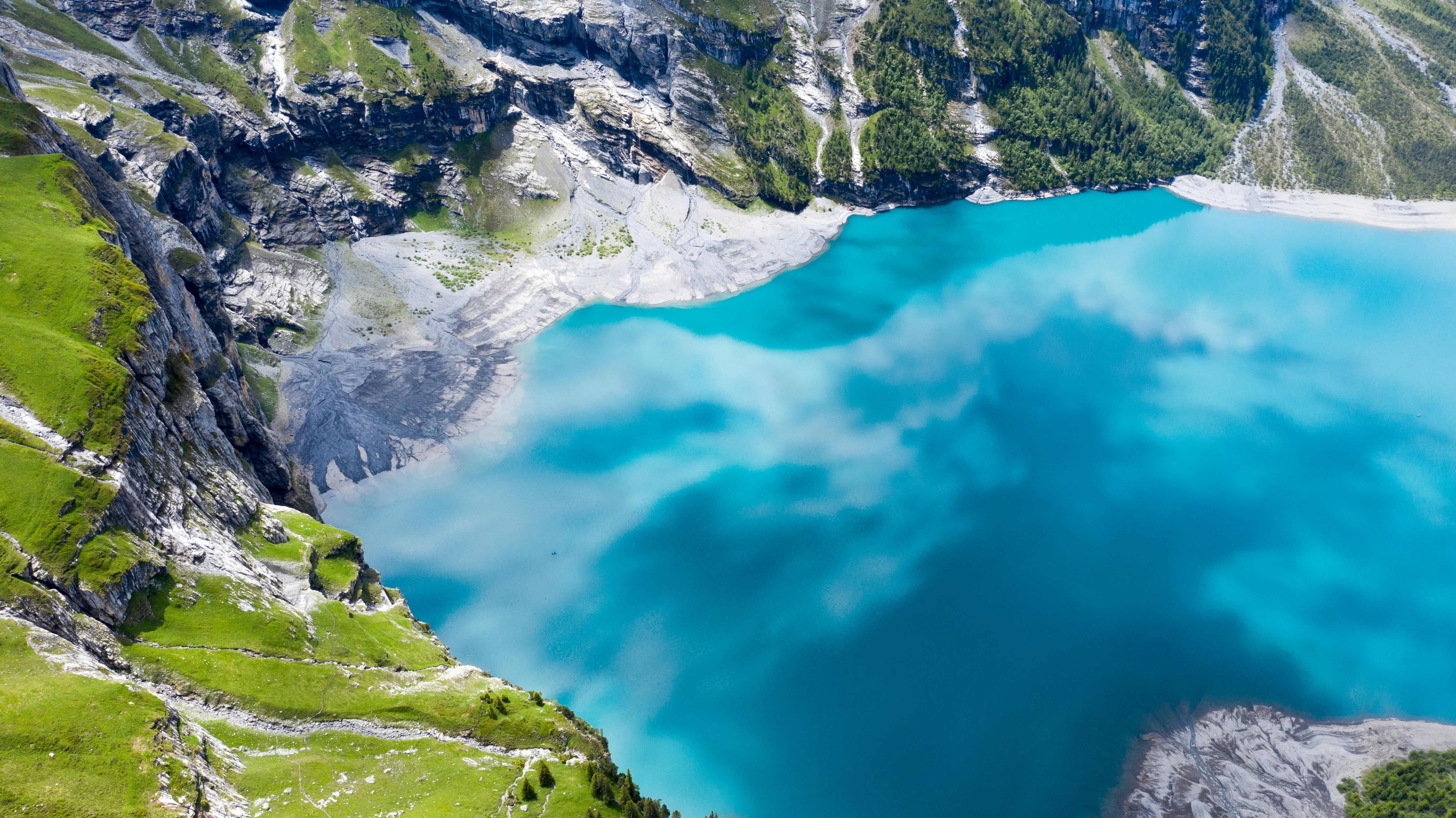 green and white mountain beside blue body of water during daytime