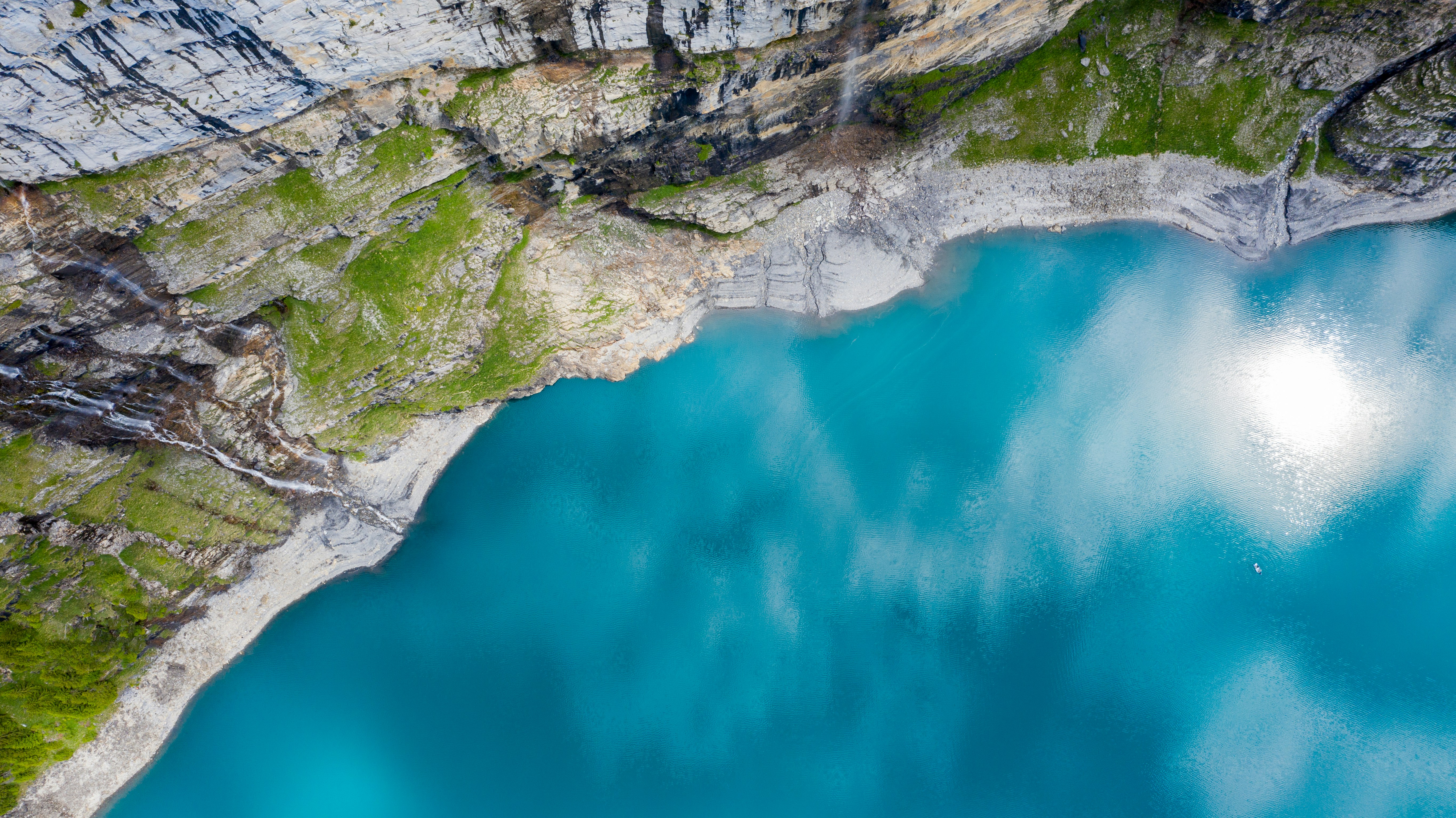blue lake between gray rocky mountain during daytime
