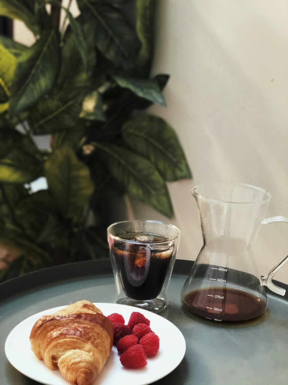 clear drinking glass beside white ceramic plate with food