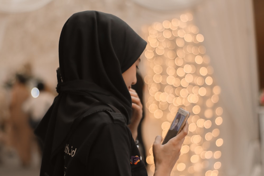 woman in black hijab using smartphone