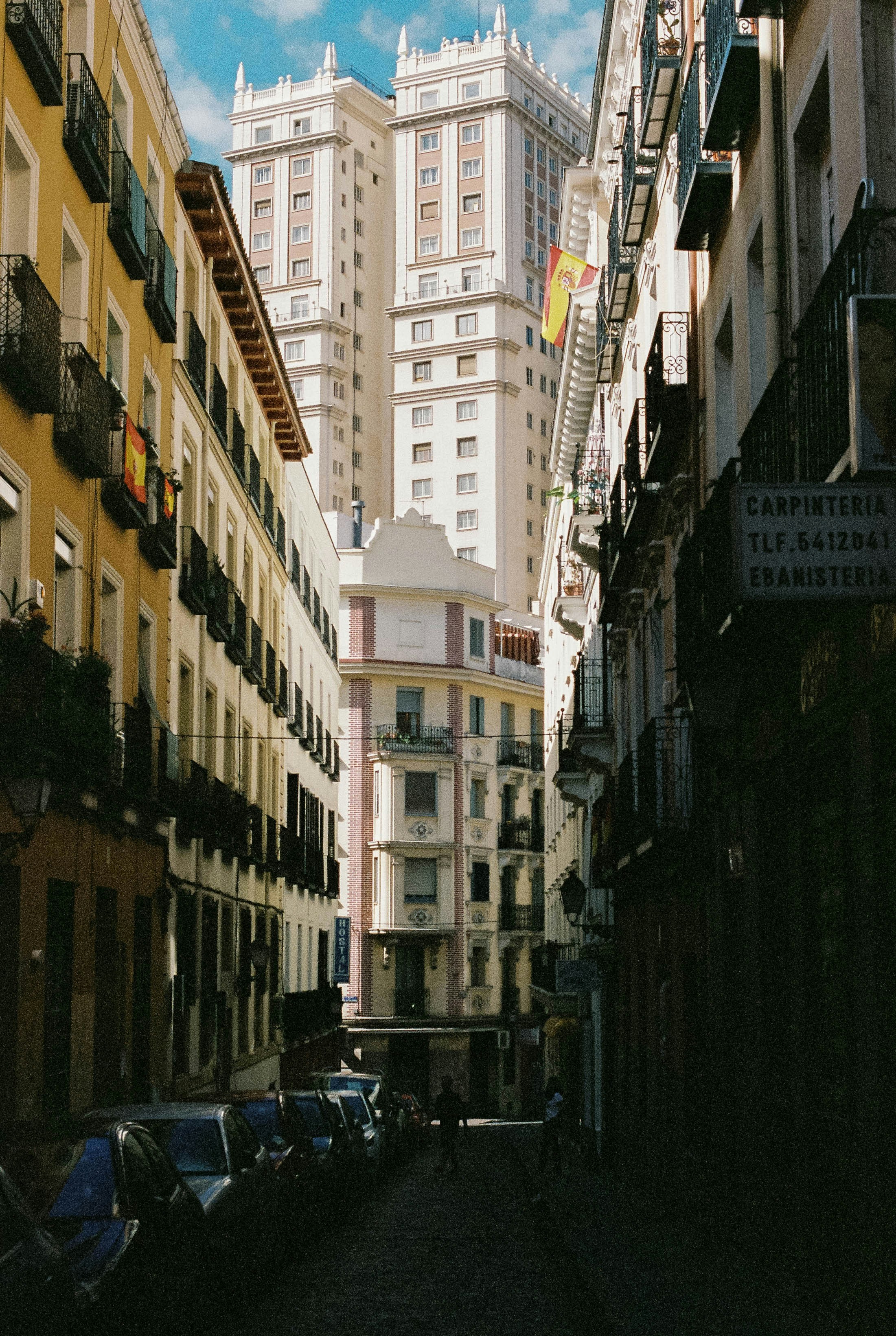 The sun shines one Edificio España viewed from a street in the shade