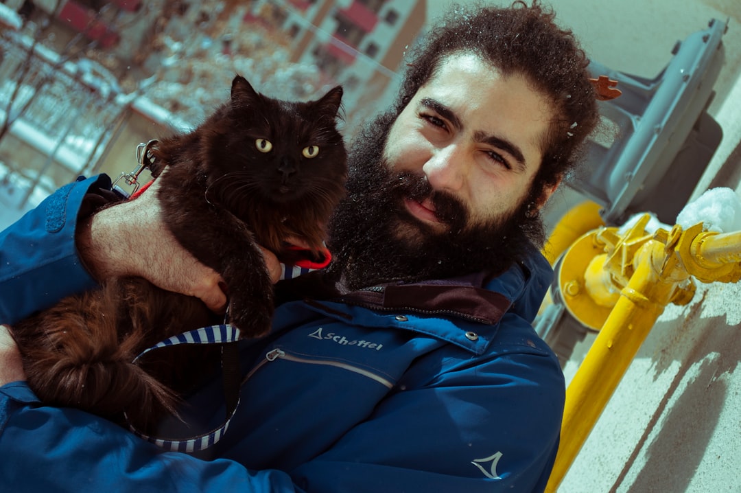 man in blue jacket holding black cat