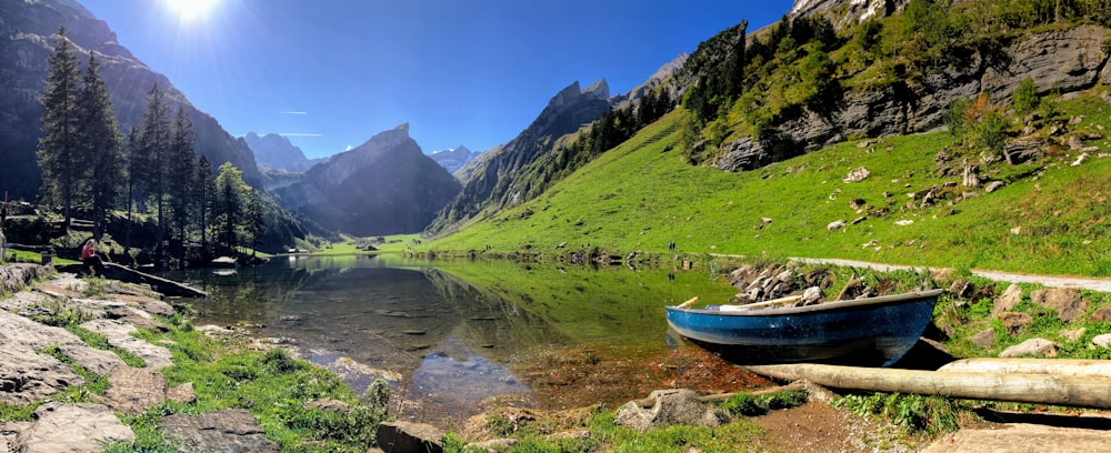 white boat on river near green grass field and mountain during daytime