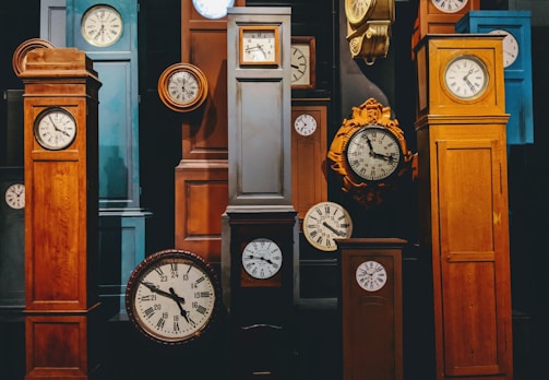 An assortment of various large clocks arranged on a wooden table.