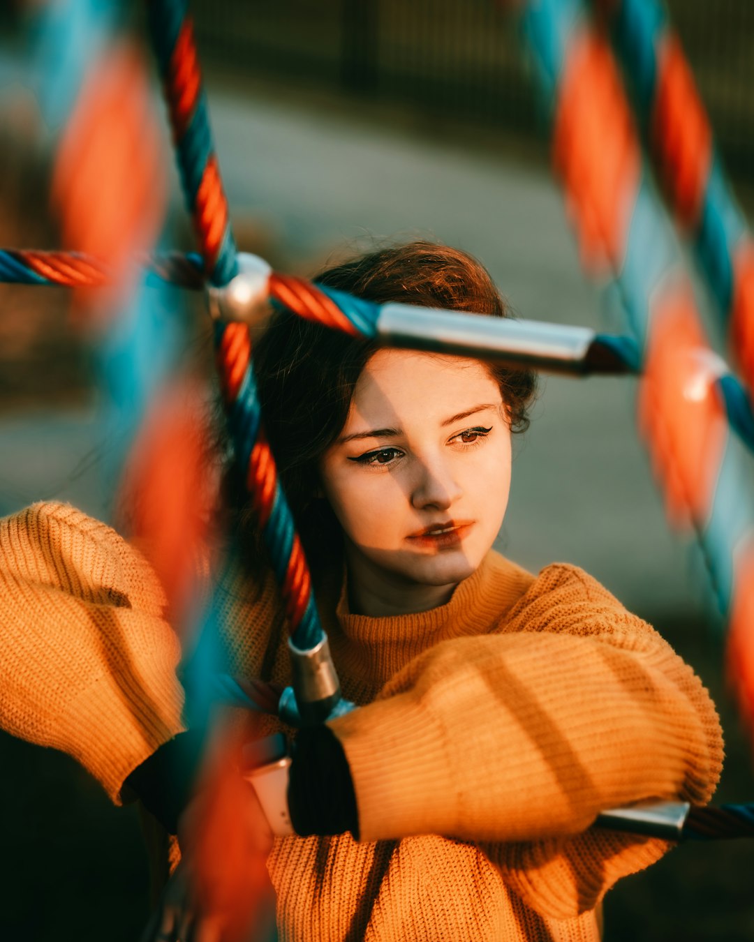 woman in brown sweater holding red and blue rope