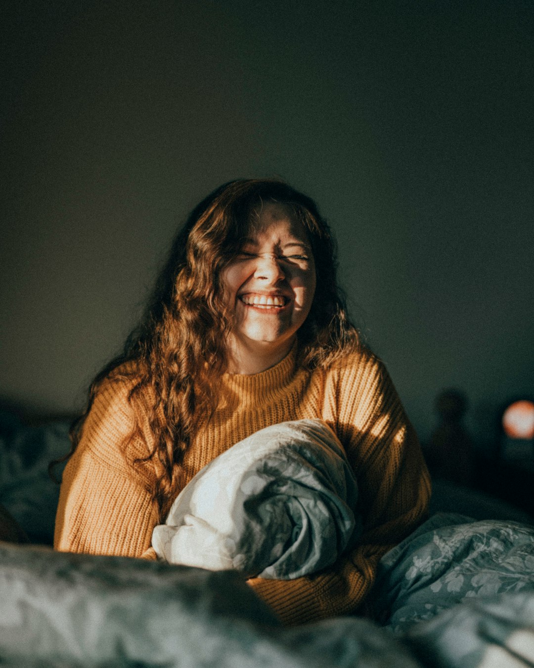 woman in brown sweater sitting on bed