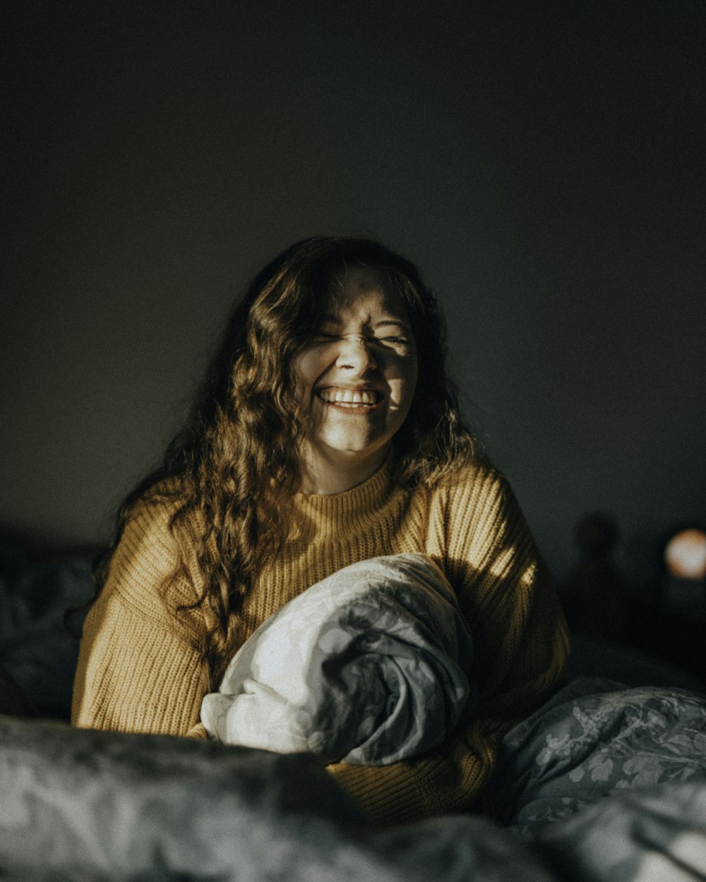 woman in brown sweater sitting on bed