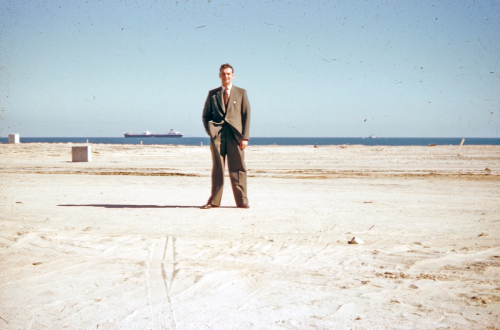 man in black suit standing on white sand during daytime