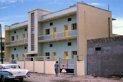 woman in white and black stripe shirt walking on brown sand near white concrete building during