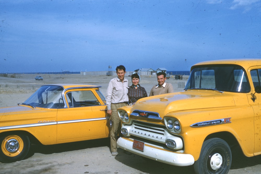 man in gray dress shirt standing beside yellow car during daytime