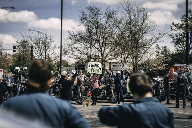 A group of diverse community members gathered outside a healthcare facility, expressing gratitude.