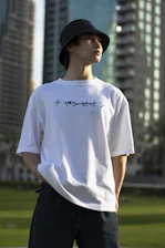 A minimalist streetwear outfit featuring a custom t-shirt against a backdrop of Stockholm’s urban skyline at dusk.
