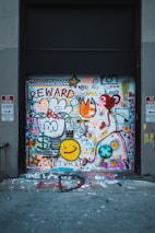 A garage door covered in colorful graffiti including various symbols, words like 'REWARD' and 'CULTURAL', smiley faces, hearts, and abstract shapes. Two no parking signs are visible on either side.
