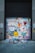 A garage door covered in colorful graffiti including various symbols, words like 'REWARD' and 'CULTURAL', smiley faces, hearts, and abstract shapes. Two no parking signs are visible on either side.