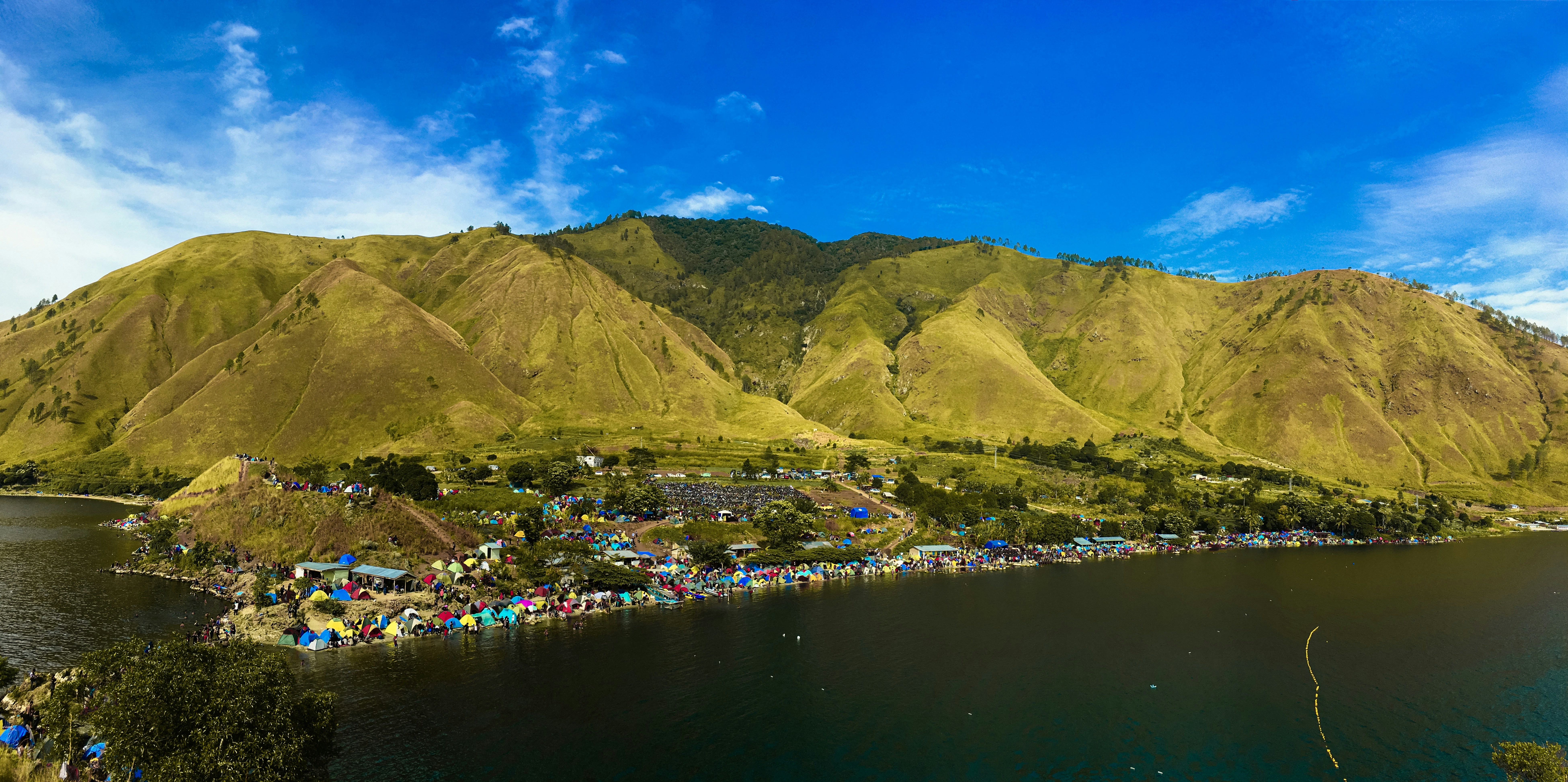 Green and brown mountains beside body of water under blue sky during daytime