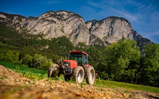 red tractor on green grass field near mountain under blue sky during daytime in Völs Austria
