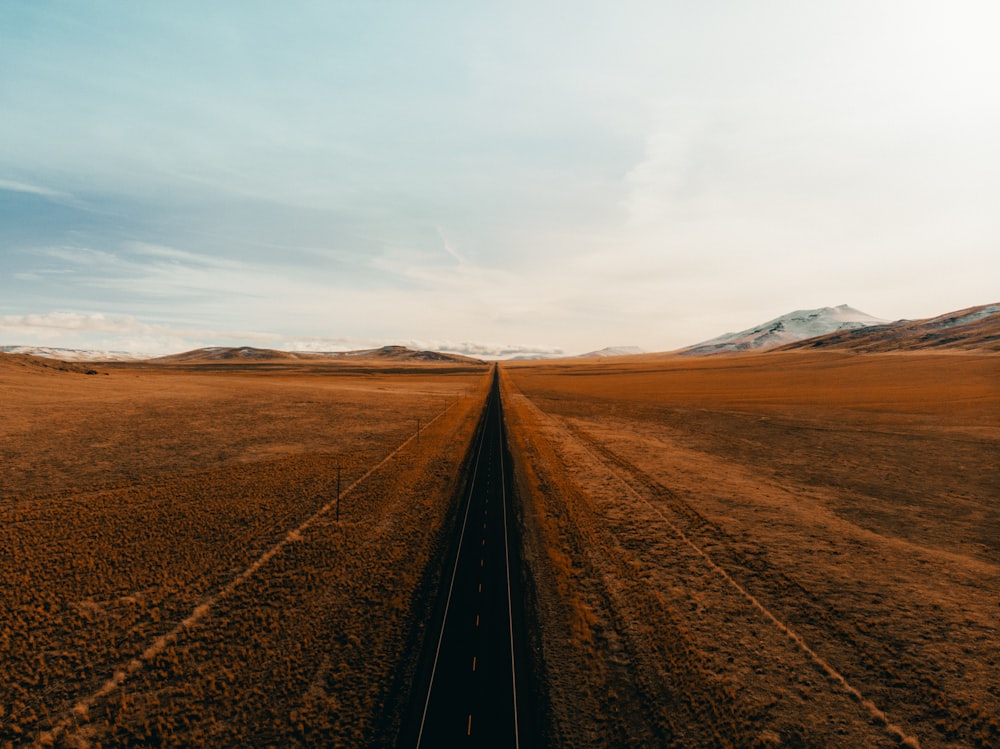 black metal train rail in the middle of brown field during daytime