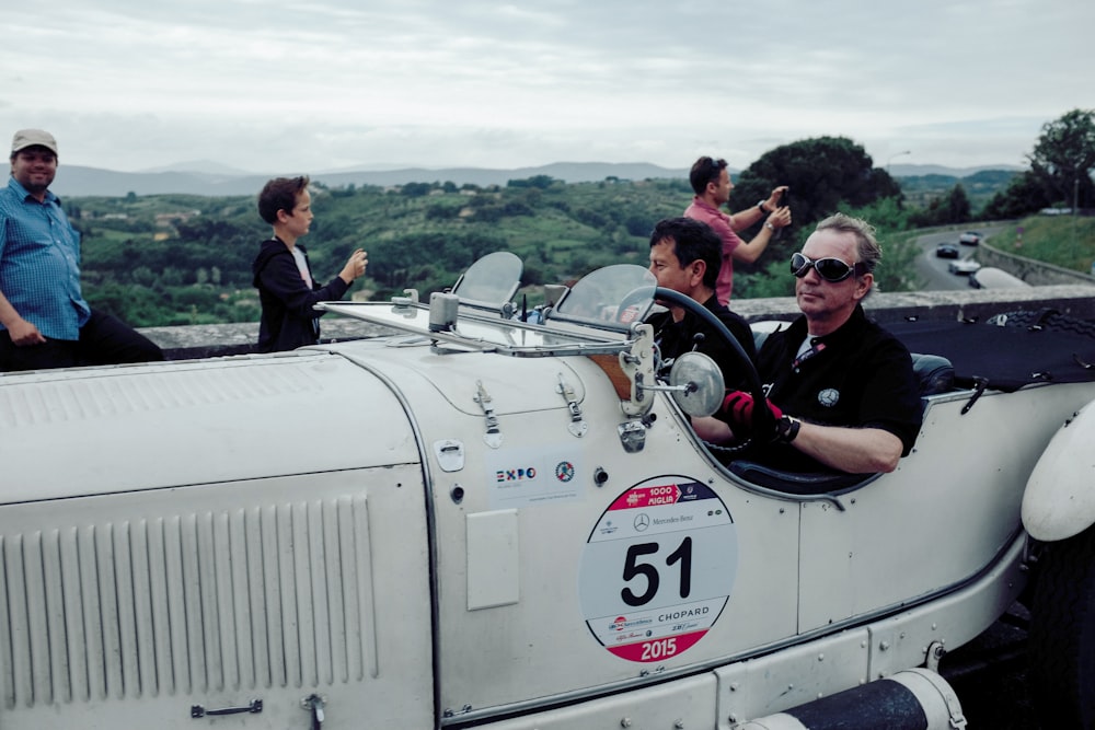 group of people riding on white convertible car during daytime