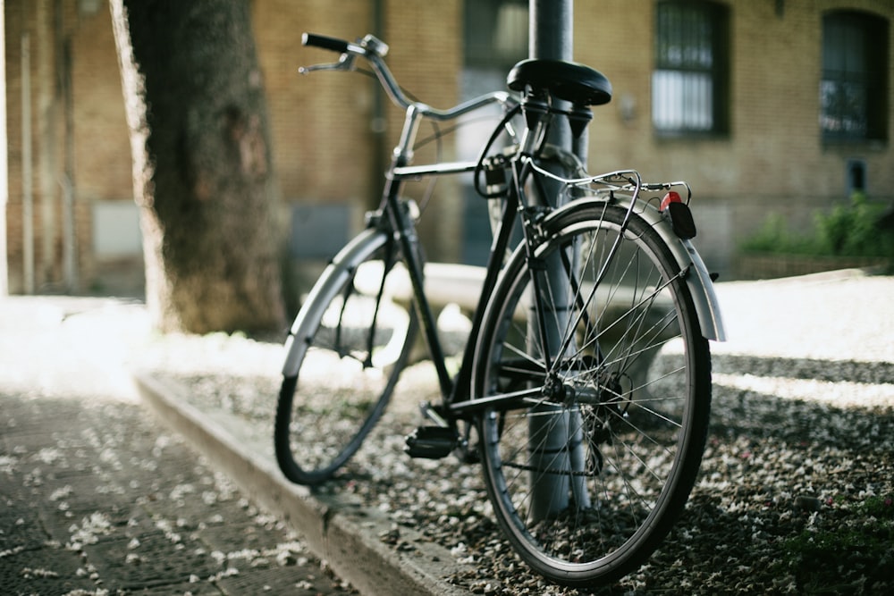 black city bike parked beside brown tree trunk during daytime