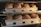 Baking trays filled with freshly baked loaves of bread inside an oven. The bread is golden brown and appears to be well-risen with crusty tops. The metal trays have multiple compartments, each holding one loaf of bread.
