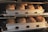 Baking trays filled with freshly baked loaves of bread inside an oven. The bread is golden brown and appears to be well-risen with crusty tops. The metal trays have multiple compartments, each holding one loaf of bread.