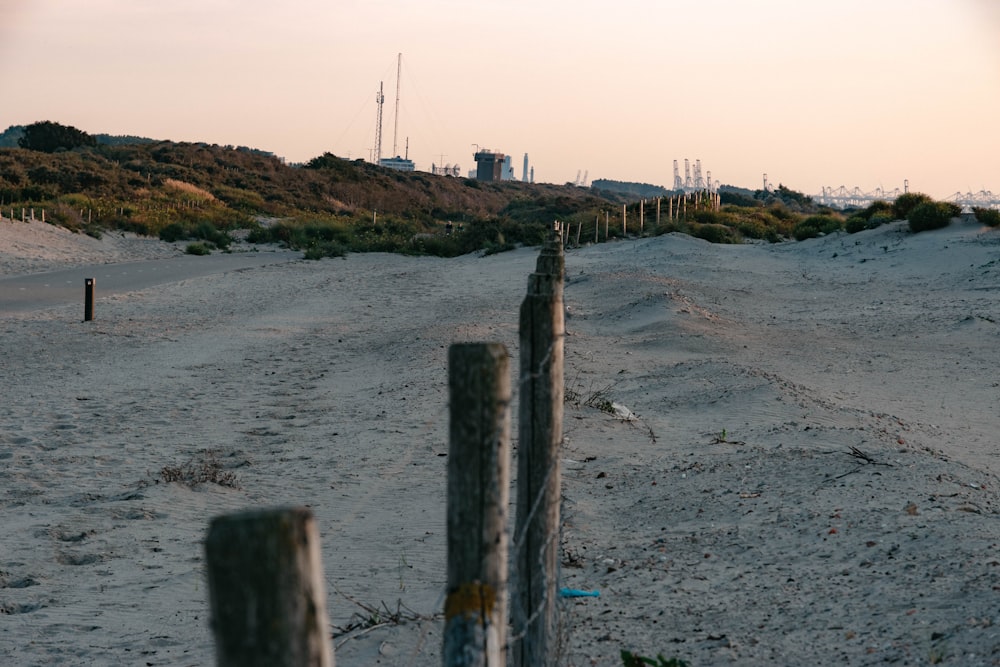 brown wooden fence on gray sand near body of water during daytime