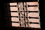 Elegant wrought iron gate with detailed scrollwork, highlighted on black background.