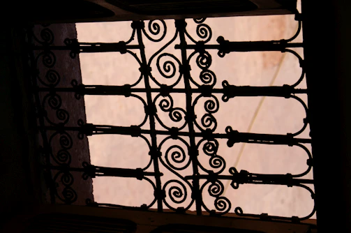 Elegant wrought iron gate with detailed scrollwork, highlighted on black background.