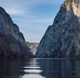 brown rocky mountain beside body of water during daytime