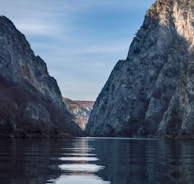 brown rocky mountain beside body of water during daytime