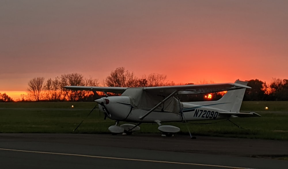Avion blanc et rouge sur le terrain au coucher du soleil