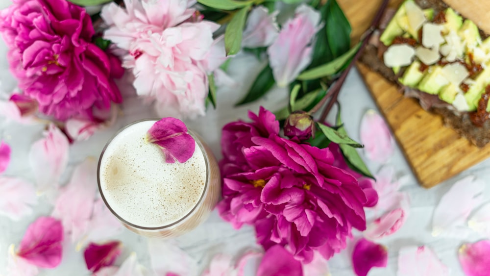 pink flowers beside clear drinking glass