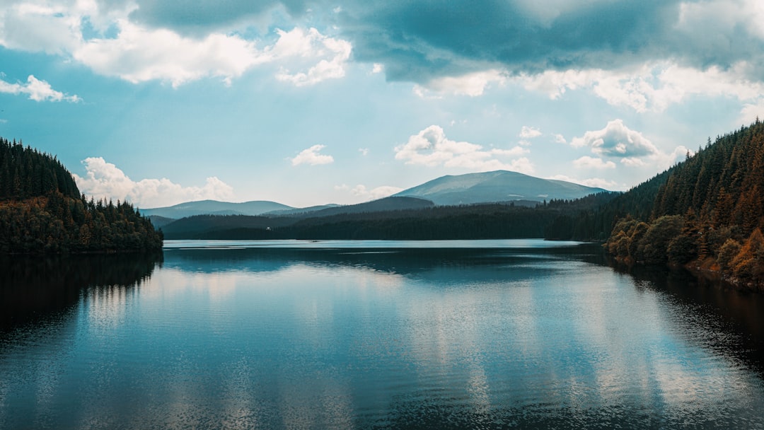 body of water near mountain under blue sky during daytime