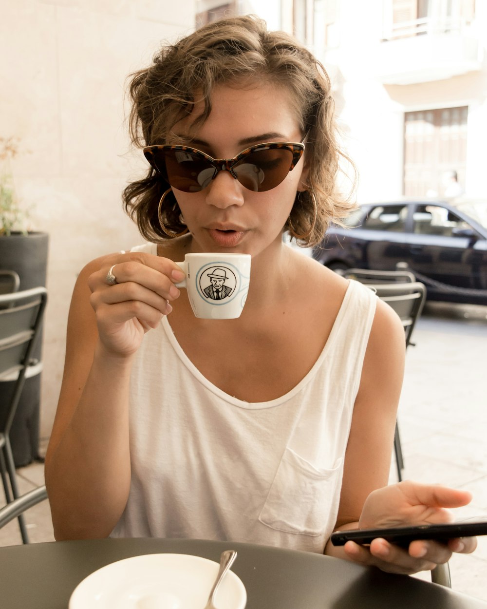 woman in white tank top holding white ceramic mug