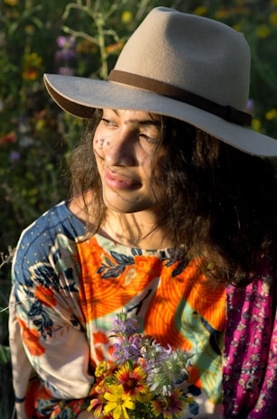 woman in white orange and blue floral shirt wearing brown fedora hat