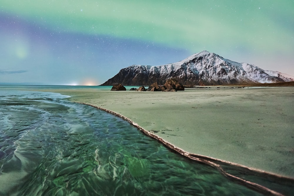 green and brown mountain beside body of water during daytime