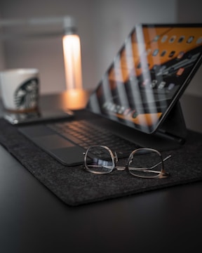 black framed eyeglasses on macbook pro