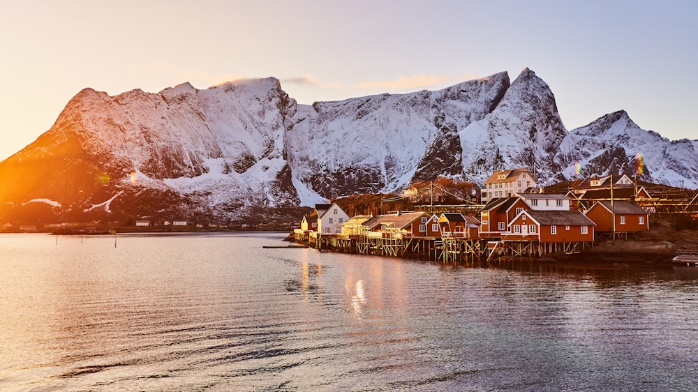 brown wooden house on body of water near mountain during daytime