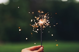 person holding sparkler with bokeh effect