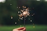 person holding sparkler with bokeh effect