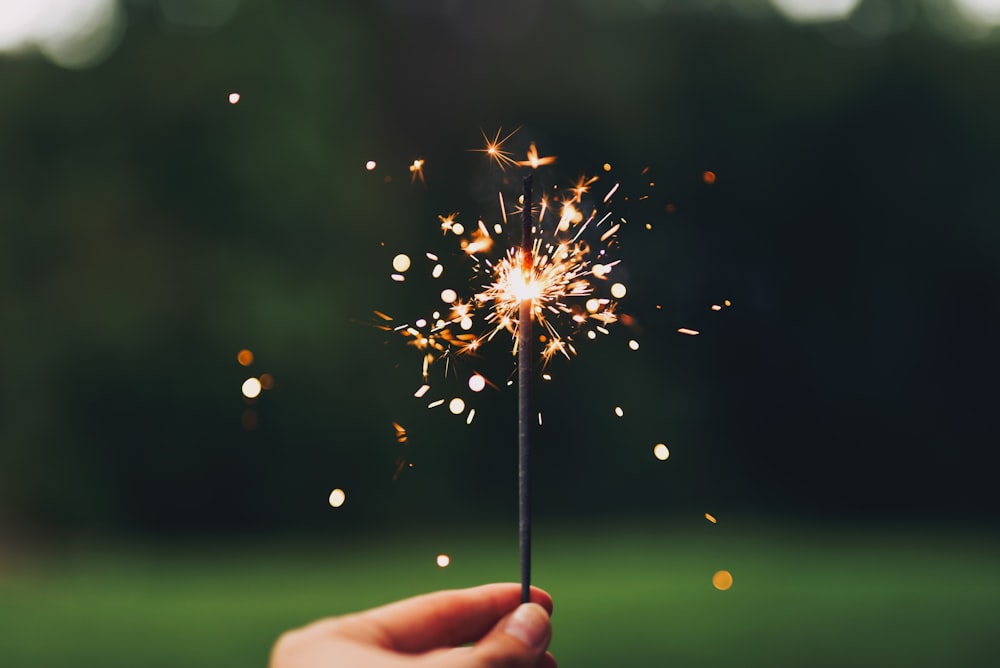 person holding sparkler with bokeh effect