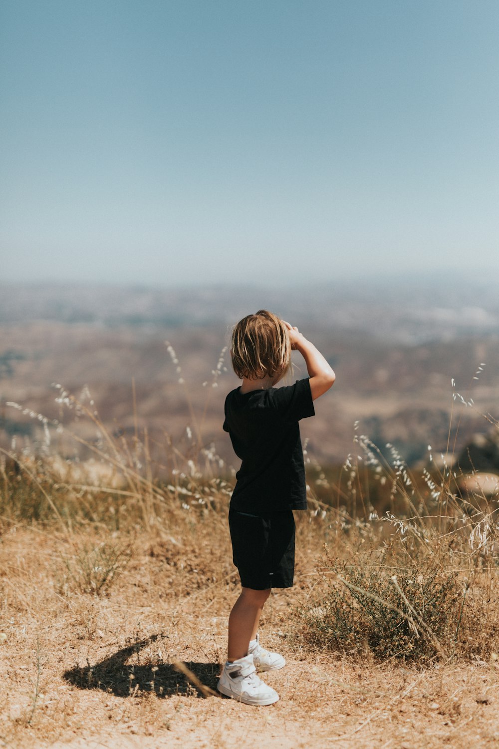 woman in black dress standing on brown grass field during daytime