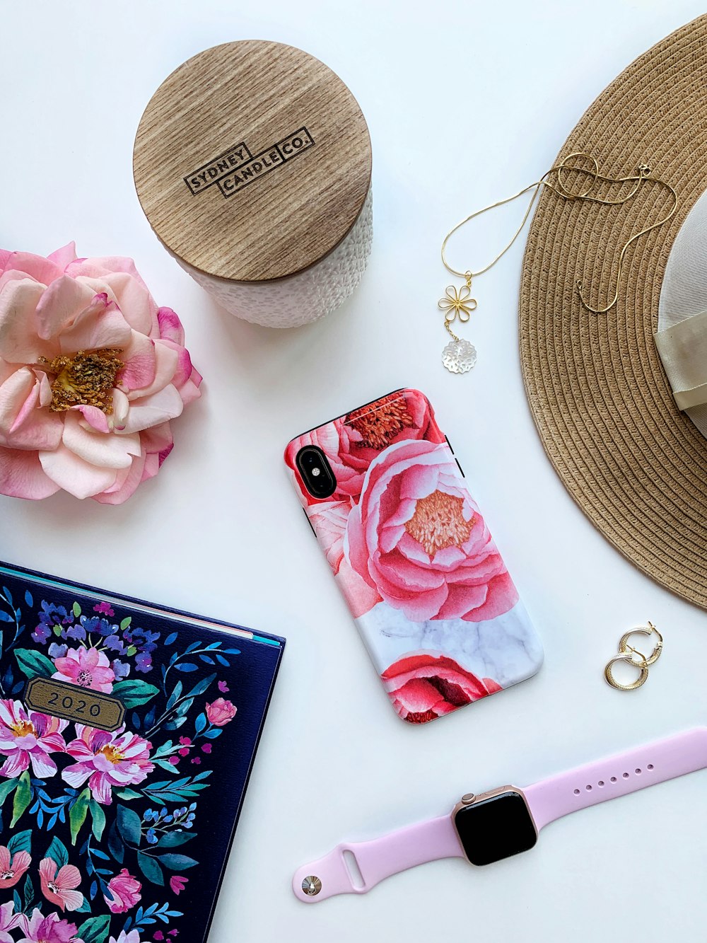 pink iphone case beside gold necklace