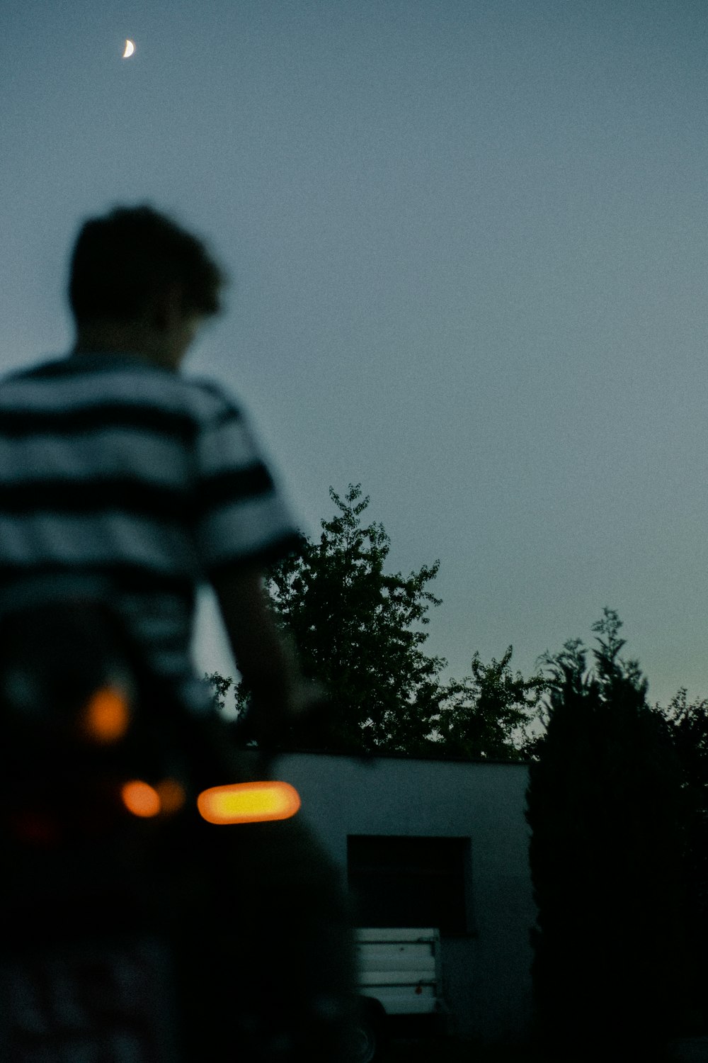 man in black and white striped shirt standing near tree during night time