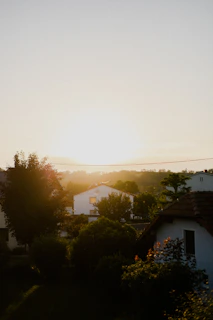 Sunset over quaint hilltop cottages with glowing windows nestled among the trees.